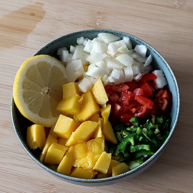 Ingredients for Spicy Mango Salsa in a shallow bowl on a working surface