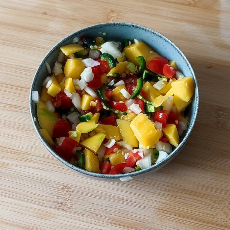 Ingredients for Spicy Mango Salsa mixed together in a shallow bowl on a working surface