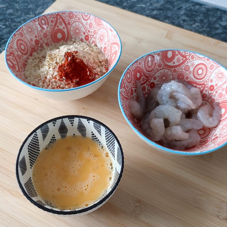 'Crispy Shrimp Station': Whisked egg in small black and white patterned bowl, seasoned panko crumbs in a red and white paisley patterned bowl and shrimps red and white paisley patterned bowl