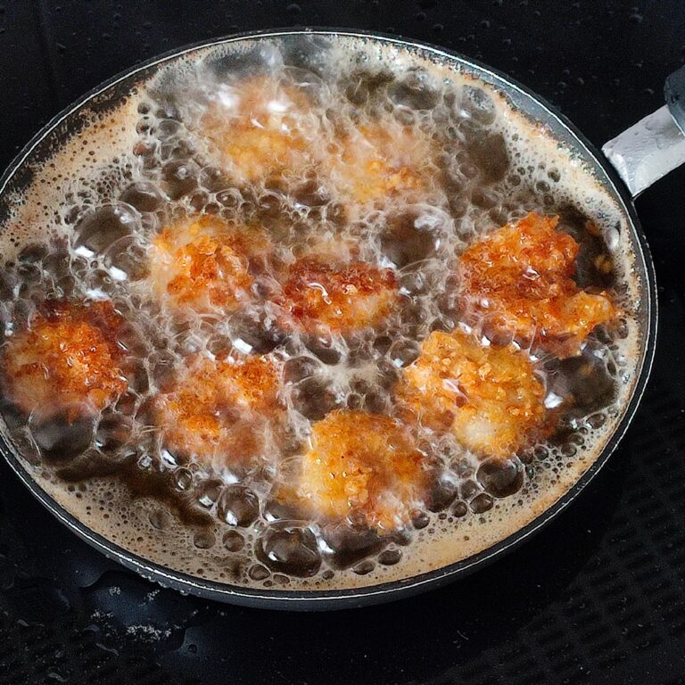 Deep frying first batch of coated shrimps in a pan