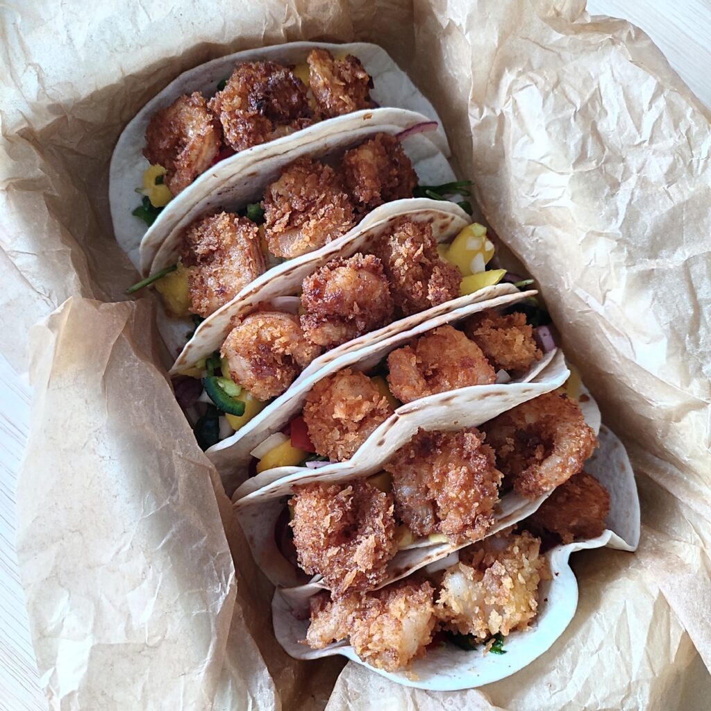 B roll 1: Crispy Shrimp Tacos with Spicy Mango Salsa in a off white casserole dish that is lined with crinkled up parchment paper on a working surface