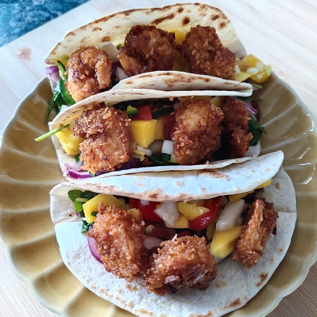 B roll 2: Crispy Shrimp Tacos with Spicy Mango Salsa on a scallop patterned ochre plate on a working surface