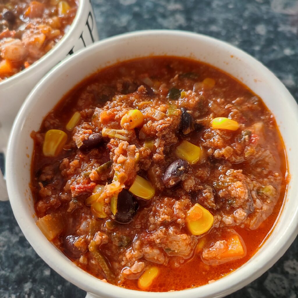 B roll 2: Close up shot of Chilli Con Carne in white patterned soup bowls with black writings on a blue grey patterned kitchen counter