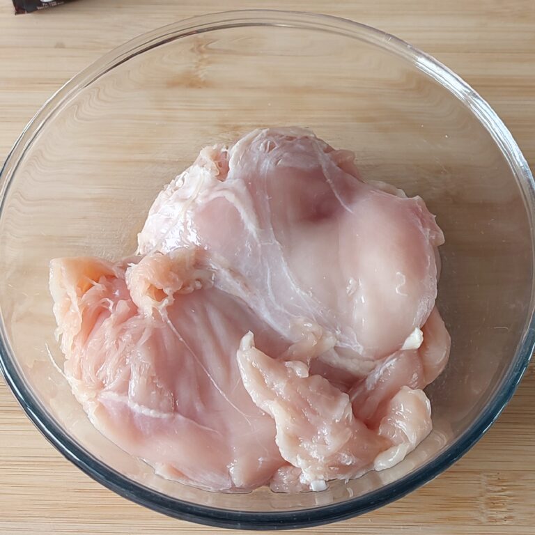 Chicken breast fillet in a large clear mixing bowl