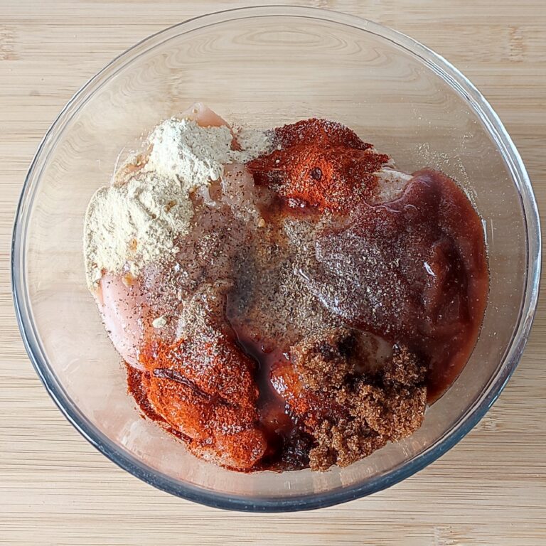 All of the spices, sauce, sugar and oil added to the chicken breast fillet in the large clear mixing bowl