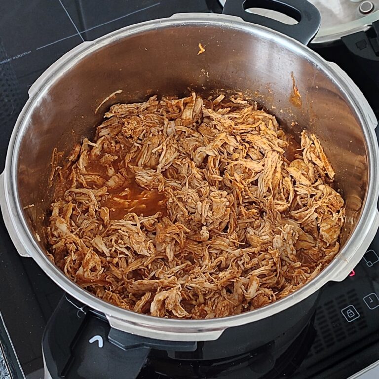 Shredded or 'pulled' chicken breast fillet cooking on the stove