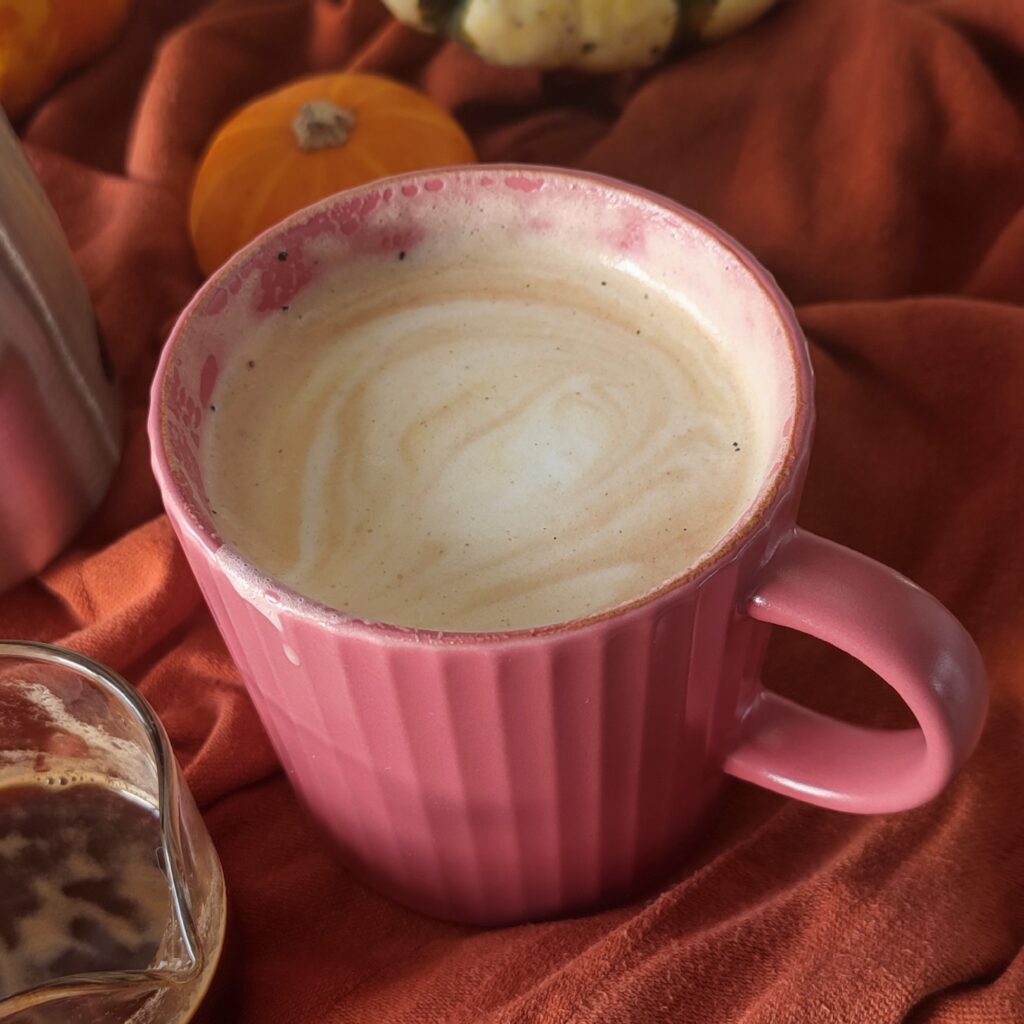 B roll 2: Drank Dirty Pumpkin Spice London Fog Latte accompanied by a shot of espresso in a shot glass with a stainless steel mug and pumpkins on burnt orange fabric