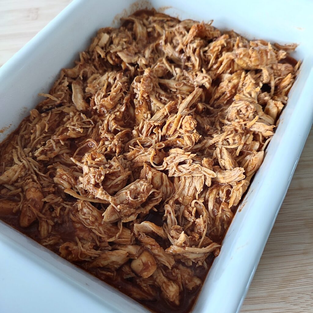 B roll 1: Instant One Pot Spicy BBQ Pulled Chicken in a white casserole dish