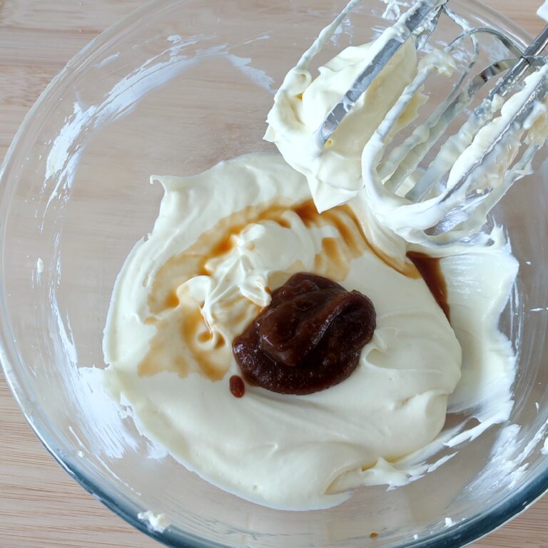 Adding pumpkin spice syrup and vanilla extract to cream cheese mixture in a large clear bowl