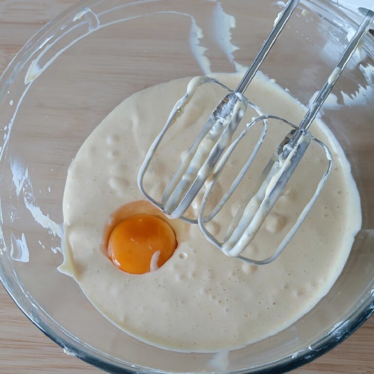 Adding a egg yolk only to cream cheese mixture in a large clear bowl