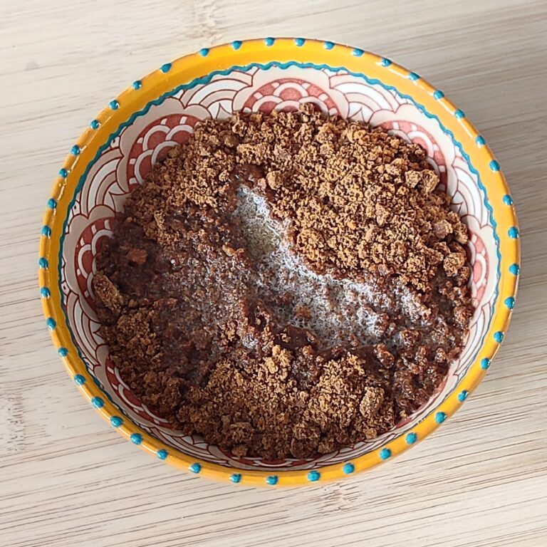 Adding butter to the crushed Bastogne cookies in patterned bowl