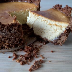 Rustic Airfryer Pumpkin Spiced Cheesecake with a slice cut and some cookie butter base crumbs on the side