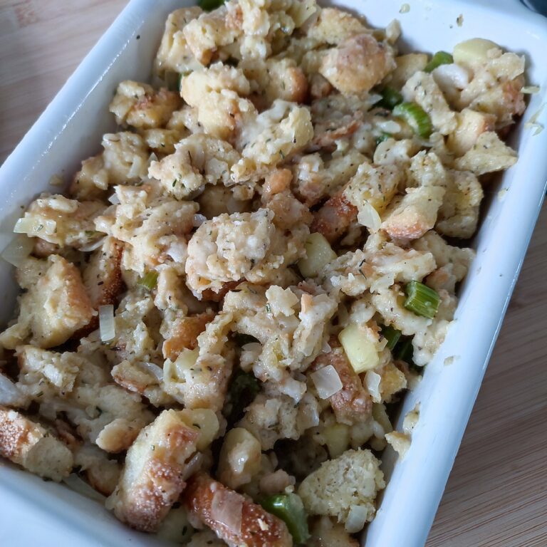 Unbaked Christmas Buttery Apple Herb Stuffing in a white coloured rectangular casserole dish