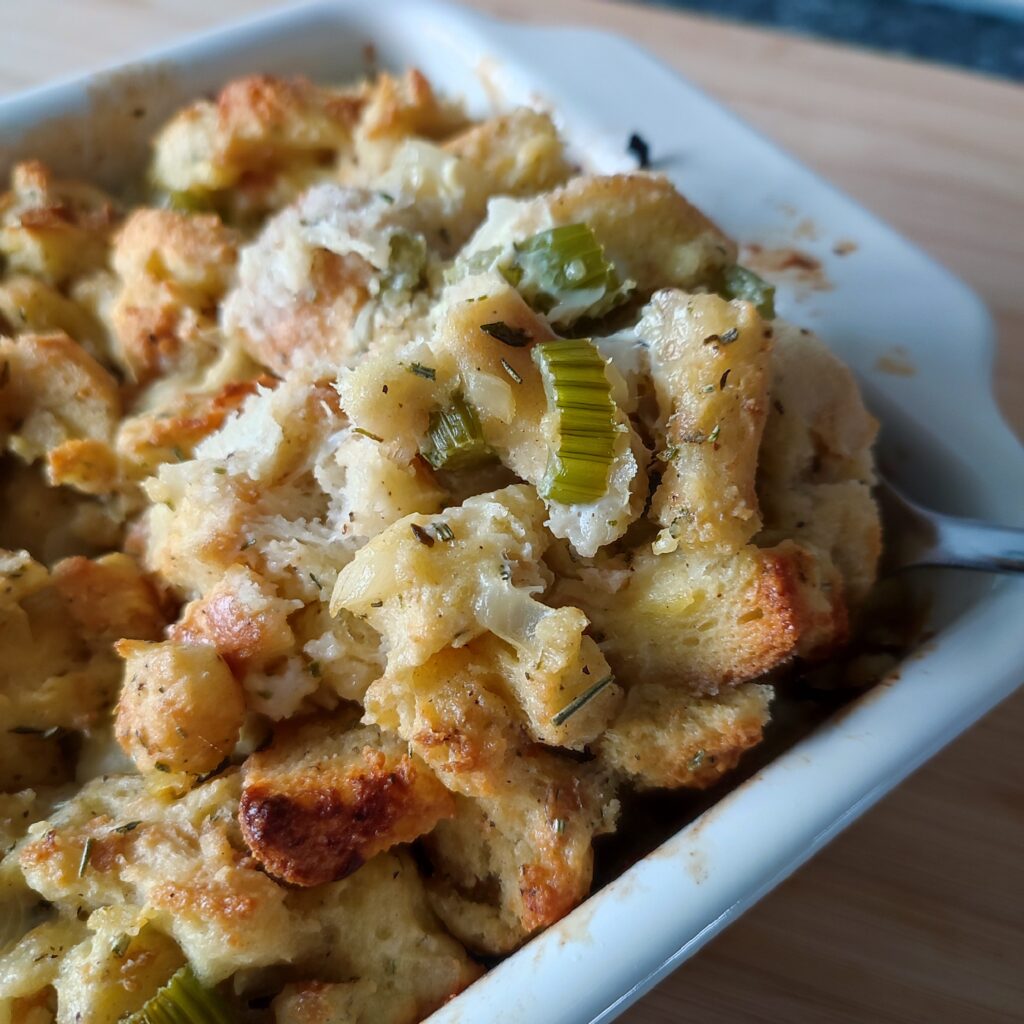 B shot 1: A scoop of Easy Christmas Buttery Apple Herb Stuffing in a white coloured rectangular casserole dish