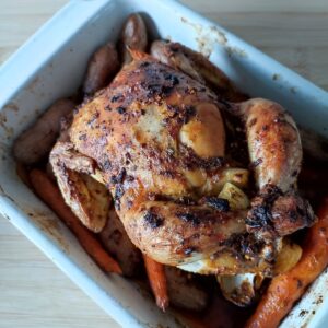 Easy One Pan Christmas Roast Chicken with potatoes and carrots in a white rectangular casserole dish