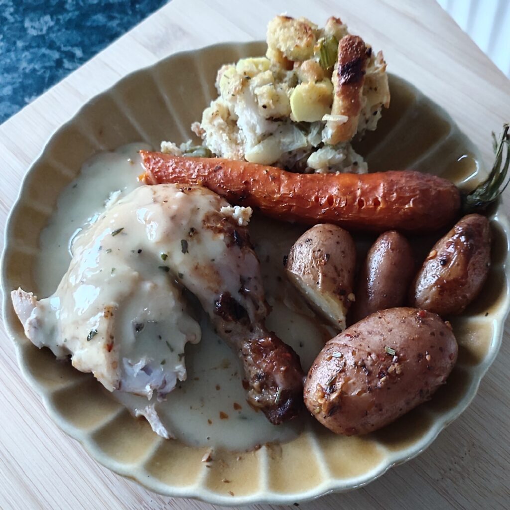 B shot 1: Slightly eaten Easy One Pan Christmas Roast Chicken with potatoes and carrots alongside Christmas Buttery Apple Herb Stuffing and glazed over with Classic Christmas Gravy on a ochre ribbed plate