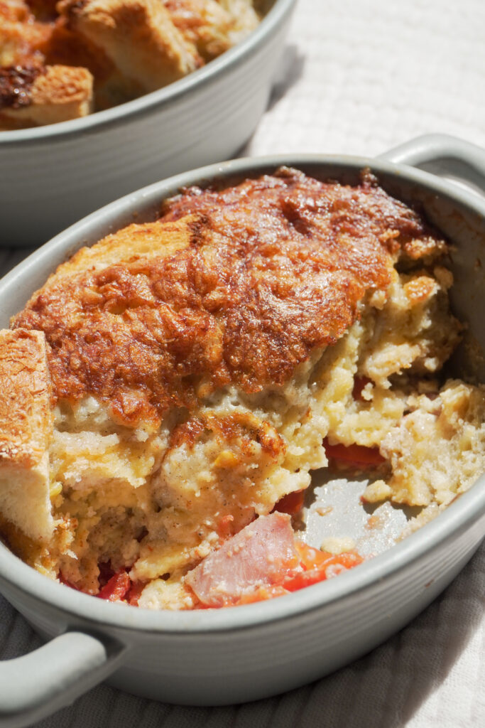 Breakfast Strata in two mini casserole dish and one is half eaten on cream coloured textured cloth side view