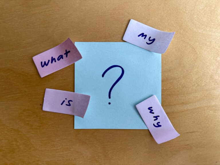 Sticky notes written 'what is my why' separately and arranged creatively around a larger sticky note that has '?' written on it
