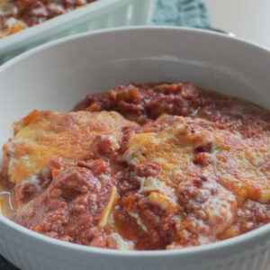 A serving of Deconstructed Lasagna in a white bowl with the rest in a casserole dish in the background