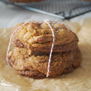 Stack of Nutella Cardamom Chocolate Chip Cookies and more cookies in the background cooling on a black wire rack