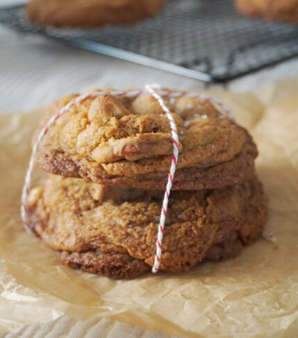 Stack of Nutella Cardamom Chocolate Chip Cookies and more cookies in the background cooling on a black wire rack