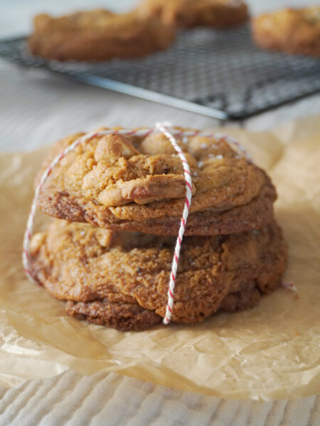Stack of Nutella Cardamom Chocolate Chip Cookies and more cookies in the background cooling on a black wire rack