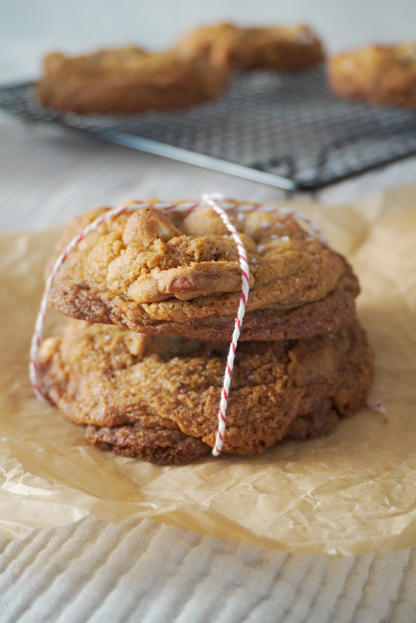 Stack of Nutella Cardamom Chocolate Chip Cookies and more cookies in the background cooling on a black wire rack