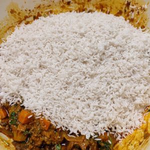 Adding soaked rice to the vegetable spice mix in a Dutch oven