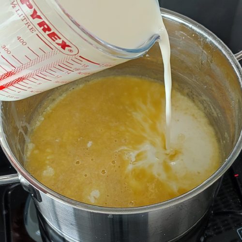 Adding milk to the roux mixture in the pot