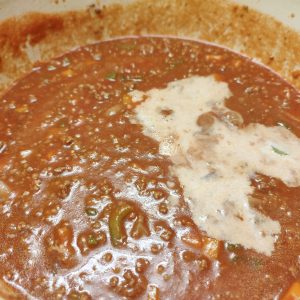 Adding passata, beef stock cubed and whole milk in Dutch oven