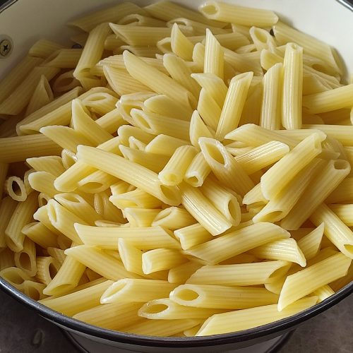 Cooked and drained penne in the pasta colander