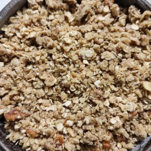 Layering the crumble mixture on the peach mixture in the baking pan