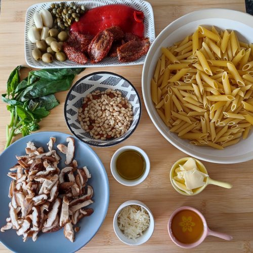 Display of ingredients for pasta rosso pesto and shiitake mushrooms on the wood surface