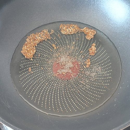 Cumin seeds and black mustard seeds tempering in hot oil in a large pan