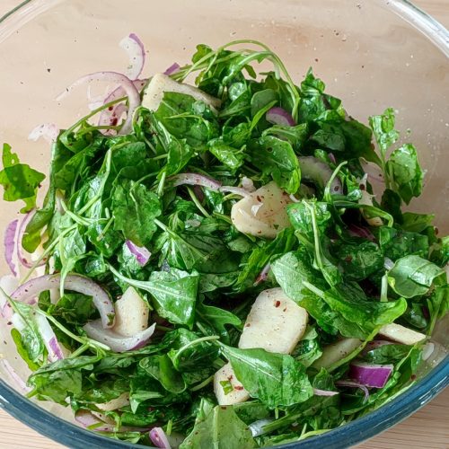 Apple Arugula Sumac Salad in a large clear bowl on the working surface ready to serve