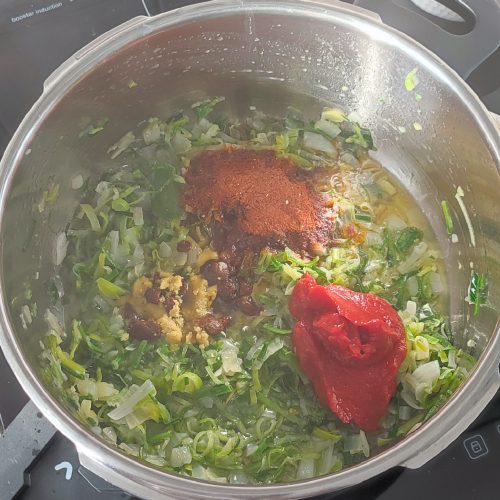 Adding spices mix, tomato paste, crushed chicken stock cube and beef stock cube in the pot