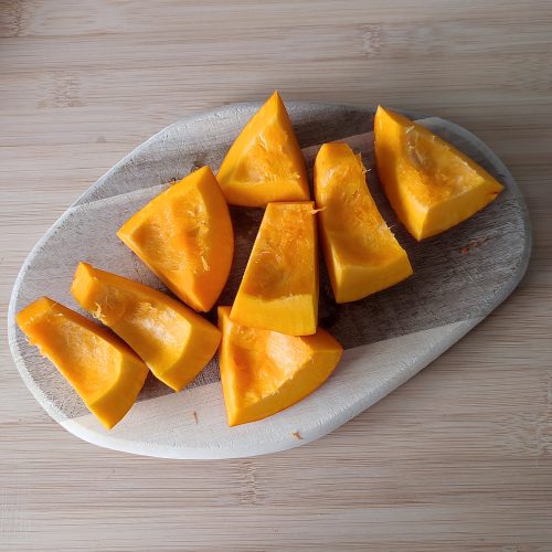 Cored and prepped pumpkin pieces on a chopping board