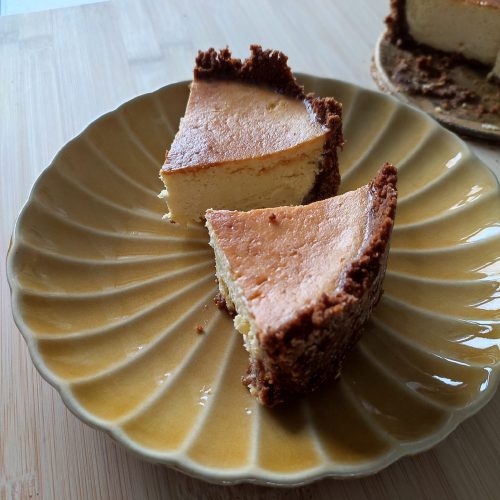 Two slices of Rustic Airfryer Pumpkin Spiced Cheesecake on ochre coloured ribbed plate