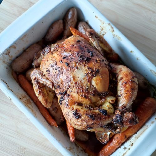 Ready to serve Christmas Roast Chicken with potatoes and carrots in a white rectangular casserole dish