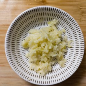 Finely minced garlic in a small plate on a working surface