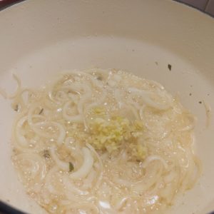 Adding minced garlic to sauteed onion in a casserole dish