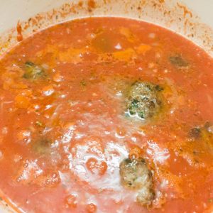 Adding polpette to the tomato based sauce in a casserole dish