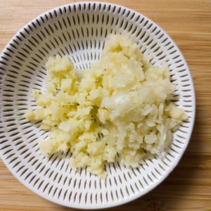 Minced ginger and garlic in a small plate on a working surface