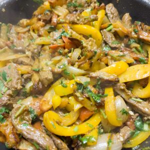 Frying all the ingredients together for lomo saltado in a pan