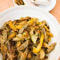 Lomo Saltado in big bowl with pita breds stuffed with lomo saltado in the background