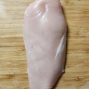 Whole chicken breast on a chopping boards