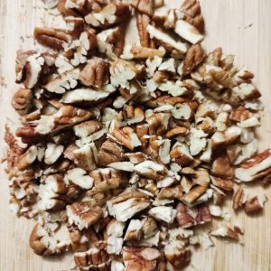 Roughly chopped pecans on a chopping board