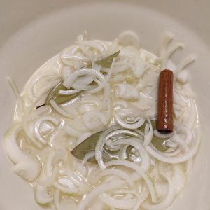 Sautéing onions, cinnamon stick and bay leaves in a Dutch oven