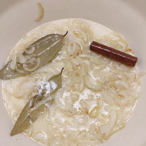 Sauteed onions, cinnamon stick and bay leaves in a Dutch oven